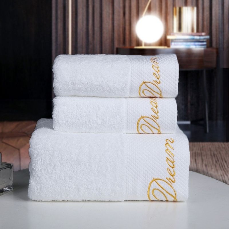 Folded bath towels with gold script embroidery