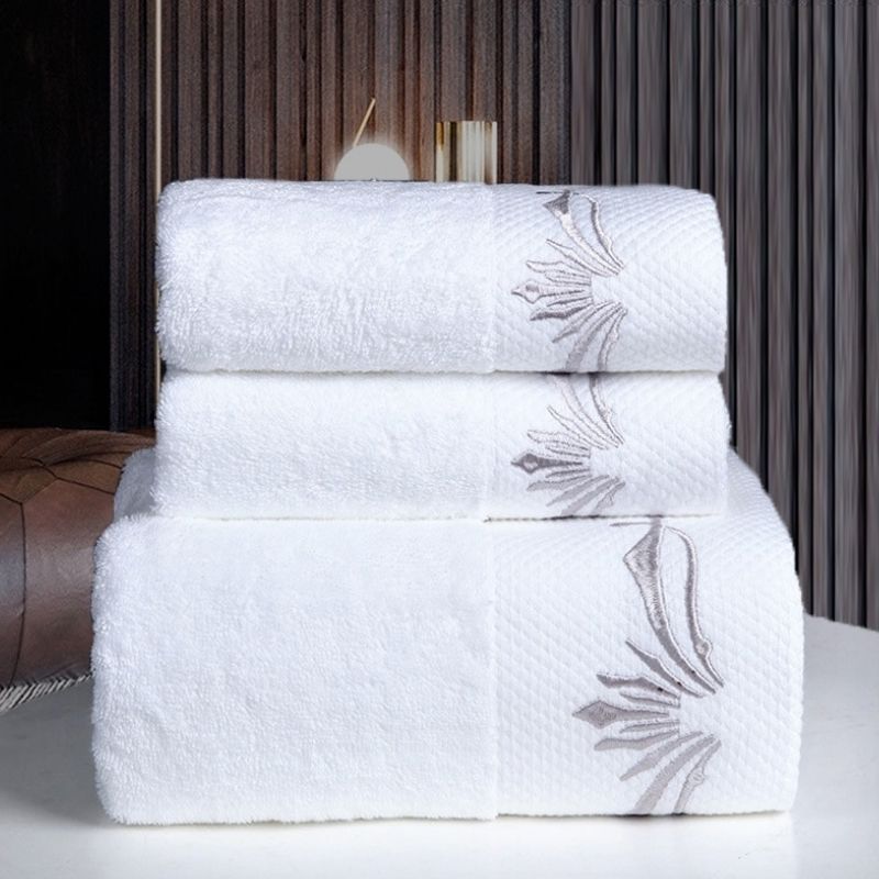 White hotel bath towels with silver embroidered motifs